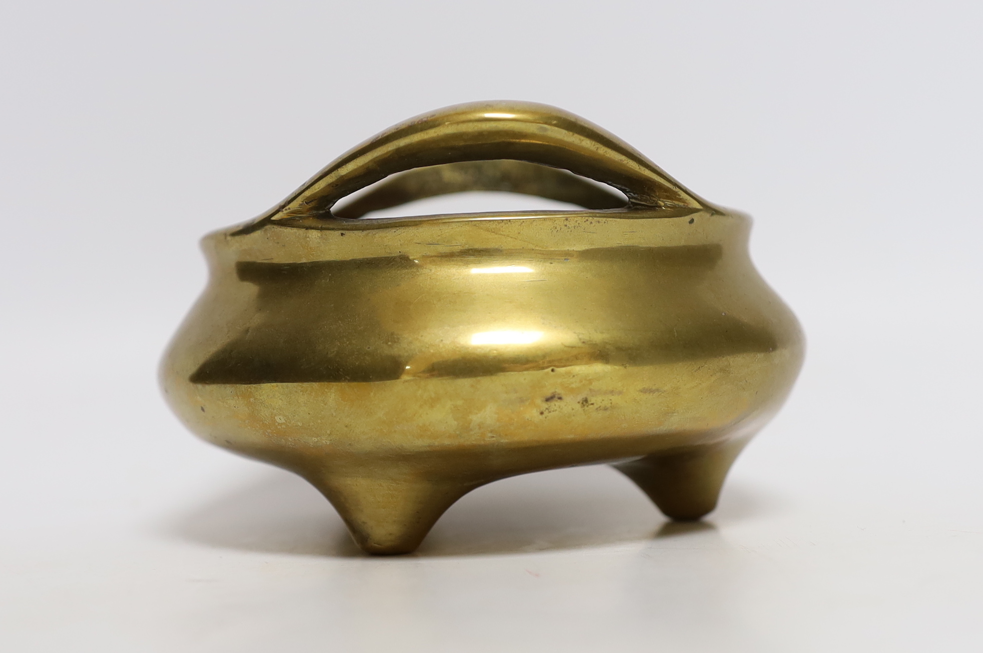 A Chinese bronze tripod censer with twin handles, mark to the base, 14cm wide